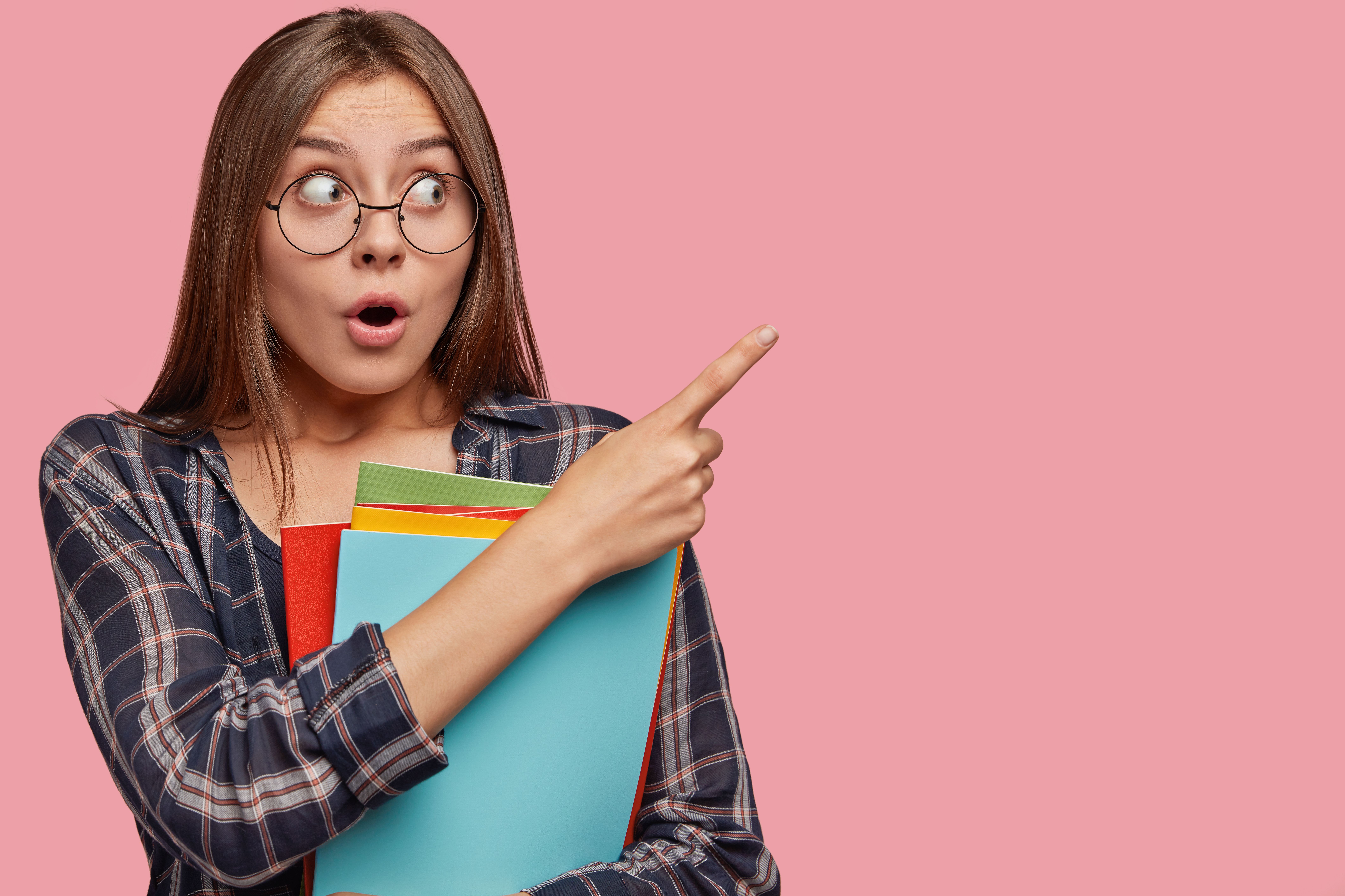 attraktive-junge-geschaftsfrau-die-gegen-die-rosa-wand-mit-brille-aufwirft.jpg